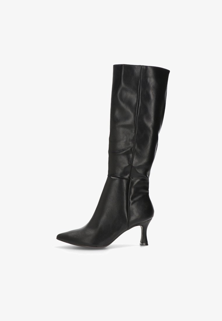 Bota de cuero negra a media pantorrilla con punta afilada y tacón delgado curvado de 5 cm, que presenta una costura vertical a lo largo del eje y un ligero fruncido en el tobillo.