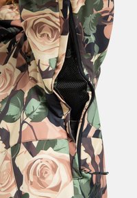 Tkanina w róże z zielonymi liśćmi oraz otwartym czarnym zamkiem mesh na ubraniu, ukazująca detale i teksturę odzieży.
