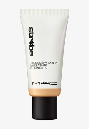 MAC Strobe Dewy Skin Tint i en hvit og gull klemmepakke med svart lokk; har et stilrent design og klar merking i mørk skrift.