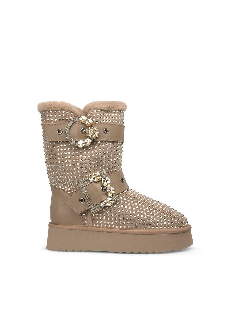 Beige enkelboot met een platte zool, versierd met strassstenen, voorzien van een bontvoering en twee accentriemen met juwelen gespen.