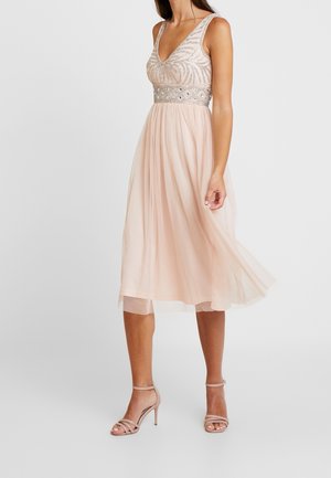 Różowa, bezrękawnikowa sukienka midi z górą z dekoltem w kształcie litery V ozdobioną cekinami i paskiem w talii, zwiewna spódnica w zestawie z pasującymi sandałami na wysokim obcasie z paskami.