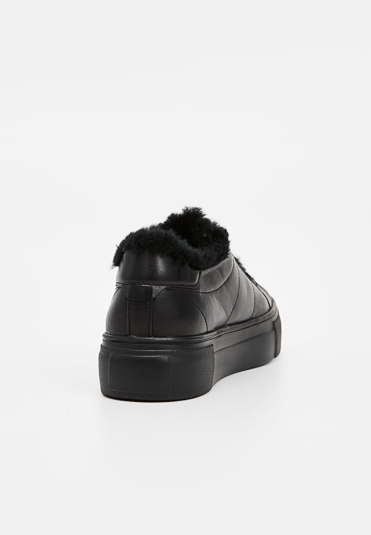 Schwarze Leder-Sneaker mit einem strukturierten, plüschigen Kragen, niedrigem Design und einer flachen Gummisohle. Verfügt über sichtbare Nähte und ein mattes Finish.