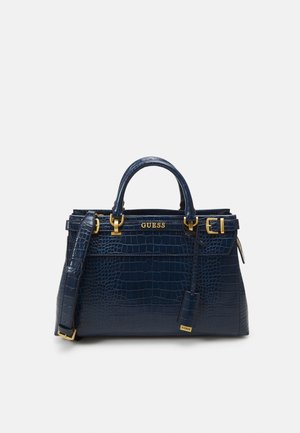 Gestructureerde navyblauwe handtas met krokodillenstructuur, dubbele hengsels, gouden hardware, afneembare riem en "GUESS" logo aan de voorkant.