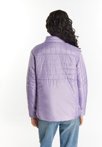 Lavender pufferjack met een gequilt ontwerp, voorzien van een afneembare kraag en een zachte textuur, gecombineerd met lichtblauwe jeans.