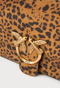 Borsa con stampa leopardata in texture suede marrone. Presenta una chiusura a forma di uccello in tono oro e accessori circolari. Marchio "PINKO."