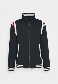 Veste noire avec un col montant, fermeture éclair, accents d'épaules rayés blancs et rouges, deux poches latérales et des poignets et un ourlet rayés.