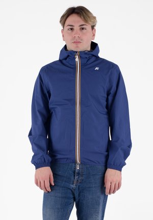 Veste bleue zippée avec capuche ajustable, poignets élastiques et zip à rayures contrastées. Le matériau semble léger et résistant à l'eau.