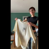 Kermanvärinen, ylipitkä t-paita, jossa on pyöreä kaula-aukko ja etupuolella graafinen printti. Paita on henkilön kädessä, joka käyttää mustaa slim fit -paitaa ja farkkuja.