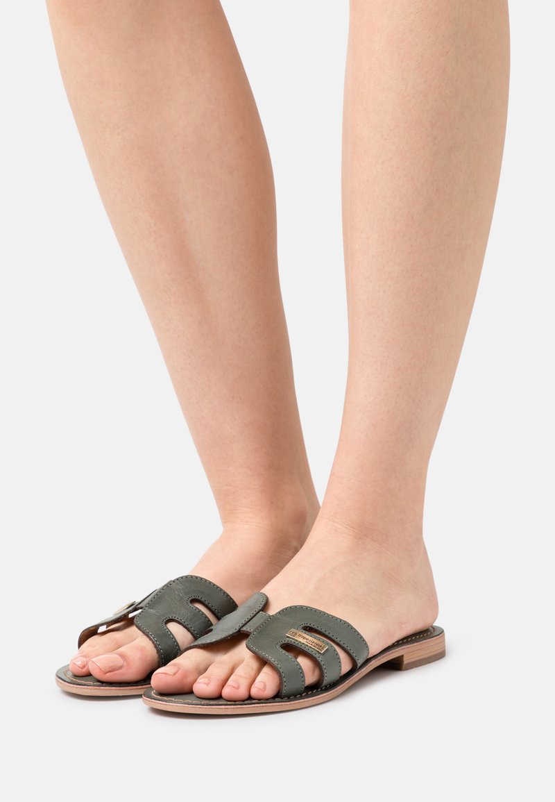 Groene leren slide sandalen met een uitgesneden ontwerp, een platte hak en een gladde textuur. Blootgestelde tenen en minimalistische hardware zijn zichtbaar.