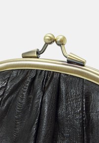 Pochette en cuir noir avec une texture froncée, encadrée par une fermeture métallique dorée ornée de boutons ronds sur le dessus.