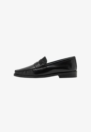 Black leather loafers with a stitched toe design and a low heel. The upper features a decorative strap. Smooth, shiny surface texture.