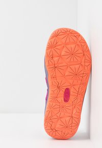 Suela de zapato de goma naranja profunda y texturizada con patrones de estrellas, rodeada de una parte superior sintética gris con acentos en rosa.