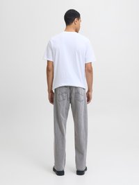 Camiseta blanca de algodón, de manga corta, corte relajado. Pantalones de denim gris, diseño de pierna recta, bolsillos traseros con un sutil detalle de costura. Zapatos negros.