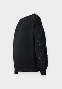 Schwarzer Pullover mit lockerem Schnitt, Rundhalsausschnitt und markanten ausgestanzten Blumenmustern an beiden Ärmeln. Glatter Stoff, gerippte Bündchen.