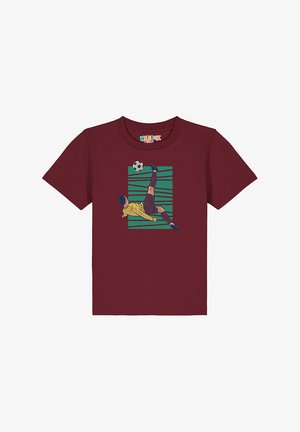 T-shirt court à manches courtes de couleur bordeaux en coton, avec un graphique d'un footballeur en mouvement sur un fond rayé vert et bleu.