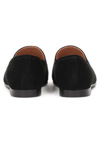 Scarpe slip-on in suede nero con punta rotonda, tacco piatto e fodera in pelle liscia. Design semplice ed elegante senza hardware visibile.
