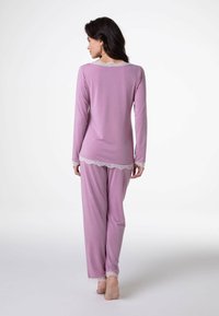 Set di pigiama rosa chiaro con maniche lunghe, bordo in pizzo sullo scollo e sui polsini, e una vestibilità comoda in morbido tessuto.