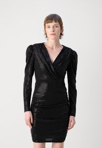 Robe noire en sequins avec des manches longues, décolleté en V profond et jupe froncée. Présente une silhouette ajustée et des épaules bouffantes pour plus de détail.