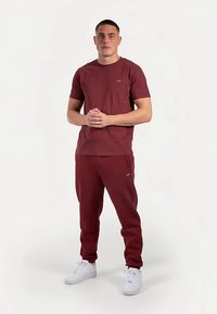 Bourgognefarvet bomuld t-shirt med korte ærmer, kombineret med matchende joggingbukser med sidelommer og hvide sportssko.