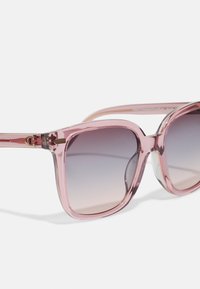 Ochelari de soare transparenti roz cu rame pătrate, lentile cu gradient care trec de la întunecat la deschis și accente de hardware aurii pe tâmple.