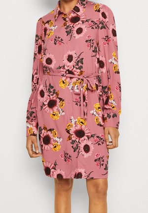 Różowa sukienka z długim rękawem, ozdobiona kwiatowym wzorem z słonecznikami i różami. Materiał ma gładką fakturę, a w talii znajduje się pasek do wiązania.