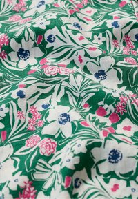 Ziedu audums ar zaļu fona, uz kura ir baltas un rozā puķes, zilas akcenta krāsas un sarežģītas lapu raksti, ar tekstūru un nedaudz krokainu virsmu.