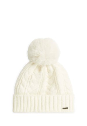 Witte gebreide wintermuts met kabelpatroon, geribde boord en grote pluizige pompon bovenop tegen een witte achtergrond.