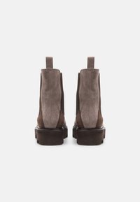 Bottines en daim marron avec panneaux latéraux élastiques, languettes de traction et semelle plateforme épaisse. Texture lisse avec un design bicolore.