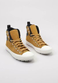 Zapatillas altas de ante con detalles en negro, que cuentan con punteras y cordones de goma blanca, además de una suela texturizada para mayor tracción.