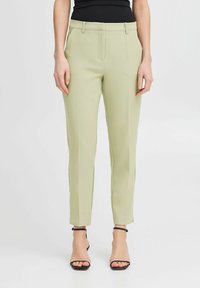 Svetlo zeleni krojeni hlače iz gladkega blaga, ki imajo ozko prileganje, ravno sprednjo stran in dolžino do gležnjev. V kompletu z črnimi sandali z naramnicami.