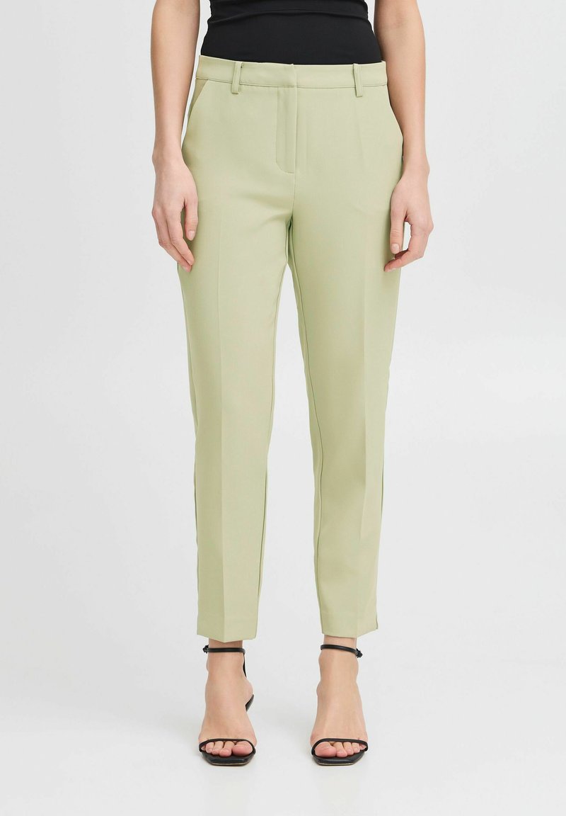 Svetlo zeleni krojeni hlače iz gladkega blaga, ki imajo ozko prileganje, ravno sprednjo stran in dolžino do gležnjev. V kompletu z črnimi sandali z naramnicami.