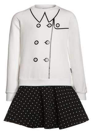 Weißes Sweatshirt mit schwarzem Druckknopf- und Kragendesign, kombiniert mit einem schwarzen Rock mit Polka-Dots. Baumwollmischgewebe, lockere Passform.