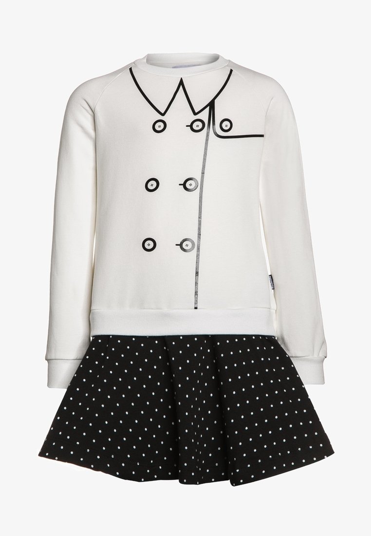 Sudadera blanca con botones y diseño de cuello impresos en negro, combinada con una falda negra con lunares. Tejido de mezcla de algodón, ajuste relajado.
