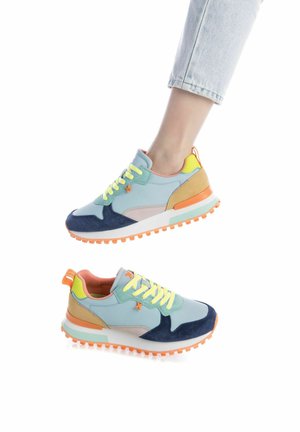 Zapatillas que presentan una combinación de ante azul claro y azul marino, cordones amarillo neón, acentos rosas y una suela texturizada naranja.