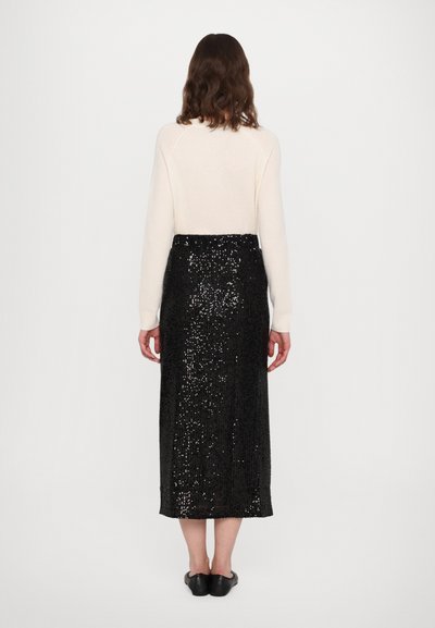 Sort paliettsyr skirt, knælang med et lige design, parret med en lys cremefarvet langærmet bluse. Glat tekstur og skinnende detaljer.
