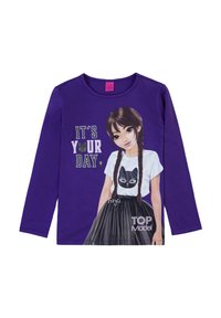 T-shirt a maniche lunghe viola con grafica di una ragazza in top bianco con stampa di gatti e gonna pieghettata nera con il testo "È IL TUO GIORNO."