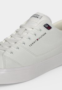 Baskets blanches Tommy Hilfiger en cuir texturé, logo de la marque sur le côté et sur la languette, et lacets blancs sur une semelle épaisse en caoutchouc.