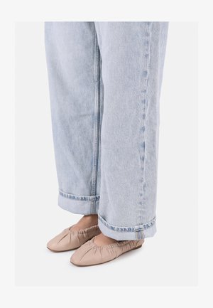 Baletní střevíce z jemné béžové kůže s nařasením vpředu, v kombinaci s volně padnoucími světle modrými džínami s ohrnutými manžetami.