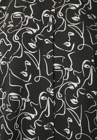 Black button-up shirt featuring a white line-drawing pattern of abstract faces. Textured fabric with five buttons visible along the front.