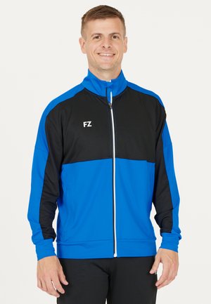 Blå og sort zip-up sportjakke med høj krave, der har hvid lynlås og logo. Lavet af glat stof med lange ærmer.