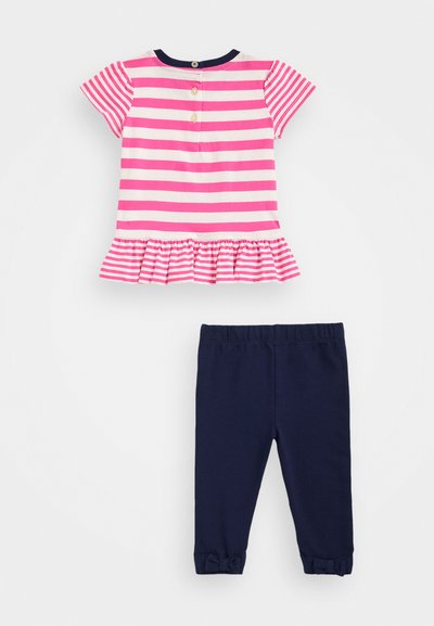 Top corto de manga corta a rayas en rosa y blanco con un dobladillo con volantes y botones en la espalda, combinado con leggings de cintura elástica en navy con detalles de lazo.