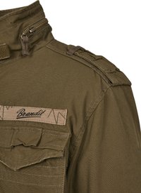 Olive green military-style jacket with a high collar, zip closure, shoulder straps, and decorative stitching. Features a chest pocket.