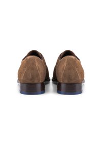 Bruine suède schoenen met een ronde neus en een lage hak, met een donkere houten zool en een contrasterende blauwe accent op de hak.