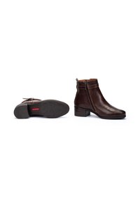 Botas de piel marrón hasta el tobillo con tacón plano, cremallera lateral y suela de goma texturizada. Acabado suave y un mínimo detalle de costura.