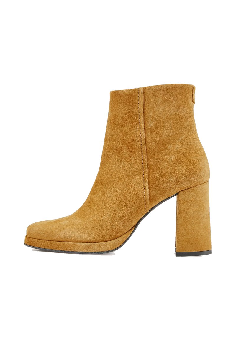 Bottine à talon bloc en daim beige, présentant une texture lisse, un bout arrondi et des détails de couture minimalistes. Design classique et couleur unie.