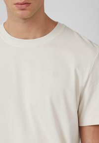 Korte mouwen, ronde hals T-shirt in off-white katoen, met een subtiele logo-detail en een effen, gladde textuur.