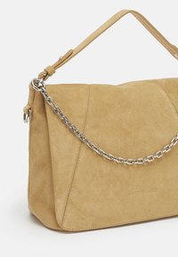 Wildleder-Handtasche in Hellbraun mit strukturiertem Design, ausgestattet mit einem silbernen Kettenriemen und abgesteppten Details. Auffälliges Logo auf der Vorderseite geprägt.