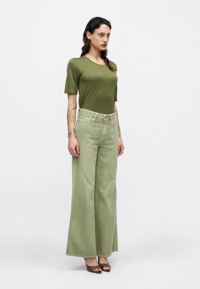 Πράσινο κοντομάνικο τοπ συνδυασμένο με ανοιχτοπράσινο τζιν παντελόνι με φαρδιά μπατζάκια. Διαθέτει στενή εφαρμογή τοπ και ψηλή μέση στο τζιν.