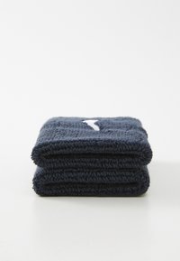 Polsino in spugna piegato di colore blu scuro con un logo bianco su una superficie bianca.