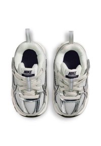 Les baskets Nike Vomero 5 présentent un dessus en mesh blanc et en synthétique argenté, une pointe ronde, des lacets, des languettes de tirage et une semelle extérieure en caoutchouc texturé.